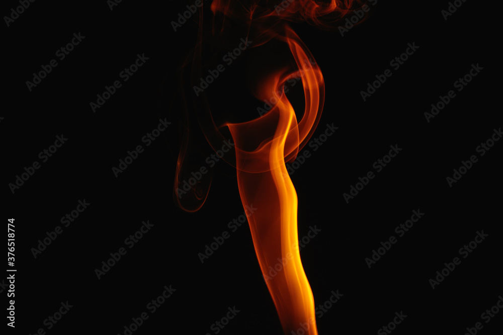 Orange smoke on a black background. Colored smoke. Smoke illuminated by orange light. Bizarre spellbinding flames.