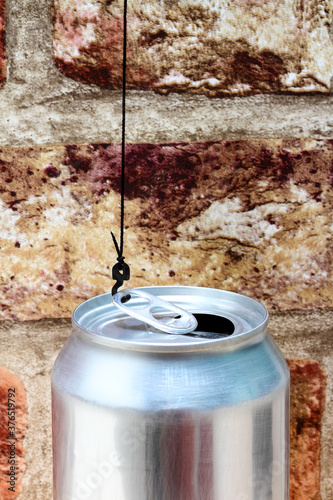 Conceptual image of a cranes hook attatched to the ring pull of an aluminium fizzy drinks can photo