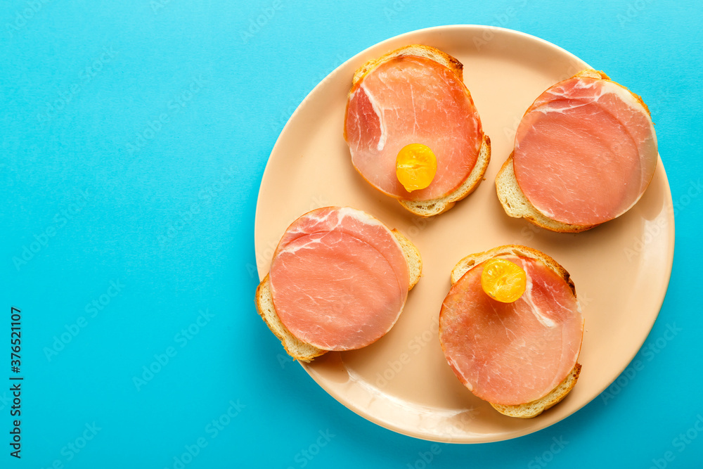 Sandwiches with ham and cherry on a plate on a blue background. Copy the place. Sandwiches with ham and cherry on a plate on a blue background. Copy the place.