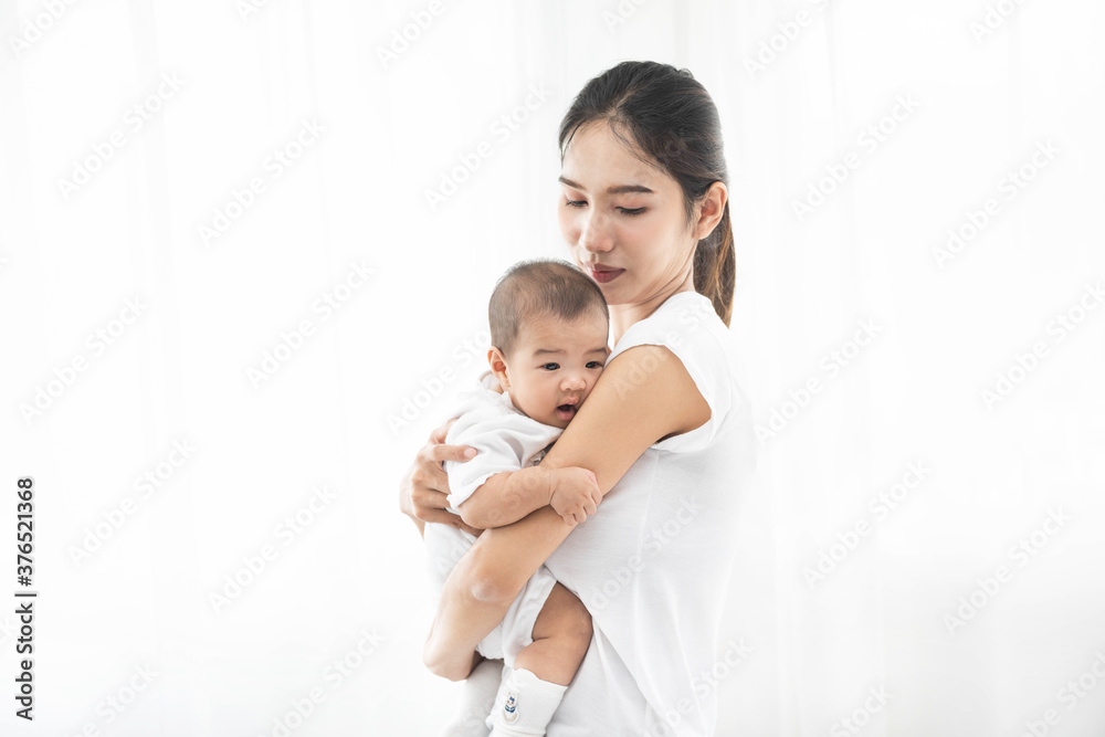 Pretty asian woman holding a newborn baby in her arms. Happy family. Laughing mother lifting her adorable infant baby son on white. Pretty asian woman holding a newborn baby in her arms. Happy family. Laughing mother lifting her adorable infant baby son on white.
