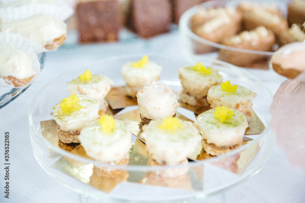 Close up of delicious mousse desserts decorated with lemon curd. Complicated french patisserie recipes. Beautiful yummy candy bar on wedding celebration. Table catering. Concept of healthy bakery. Close up of delicious mousse desserts decorated with lemon curd. Complicated french patisserie recipes. Beautiful yummy candy bar on wedding celebration. Table catering. Concept of healthy bakery.