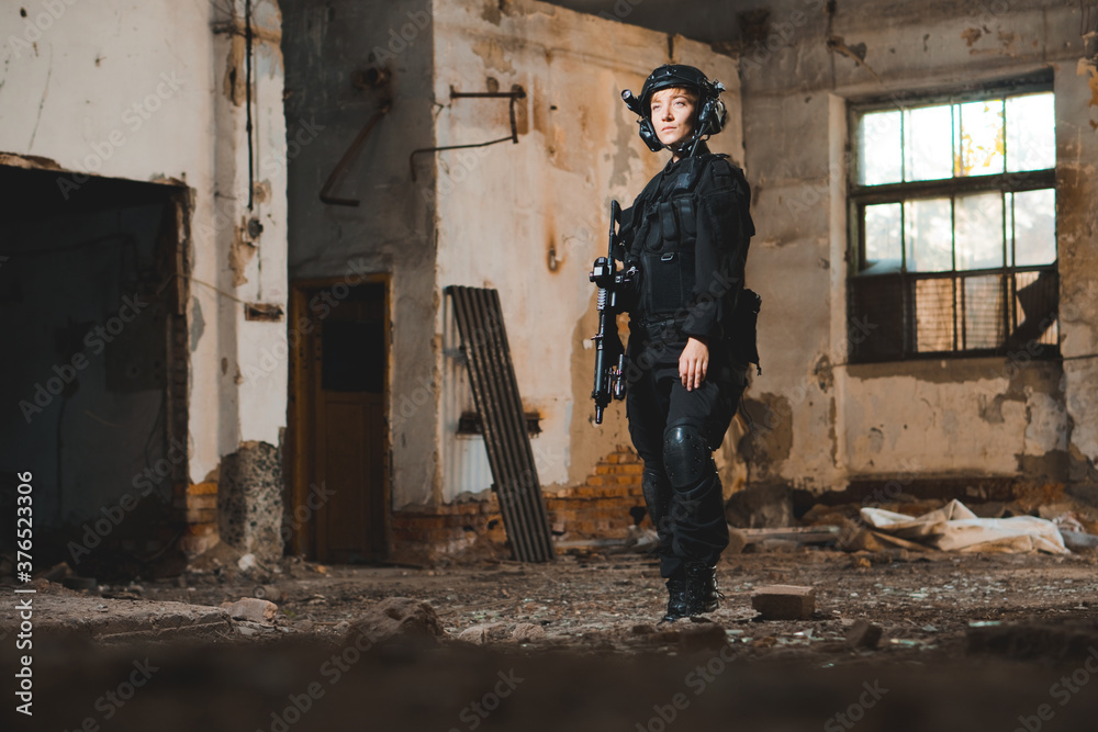 Portrait of young woman soldier in black uniform with an assault rifle. Portrait of young woman soldier in black uniform with an assault rifle.