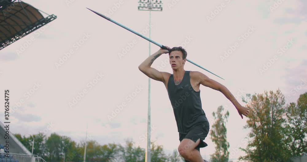 A male athlete throws javelins at a stadium in slow motion. Athletics