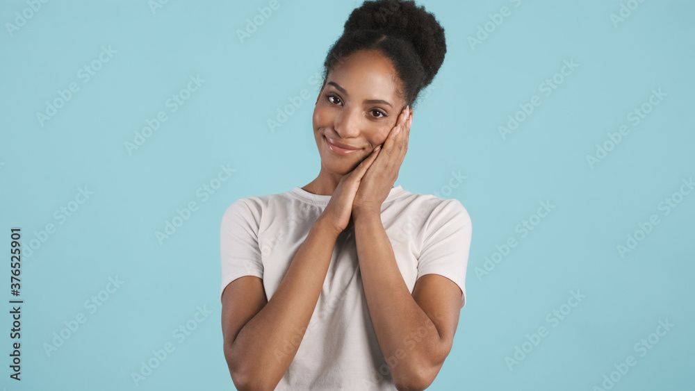 Portrait of pretty smiling afro-american girl cute posing on camera over blue background. Sleepy expression Portrait of pretty smiling afro-american girl cute posing on camera over blue background. Sleepy expression