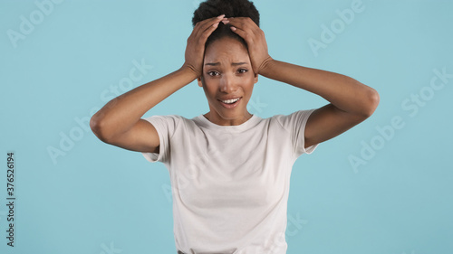 Shocked upset casual african american girl emotionally looking in camera over colorful background. Oh no expression