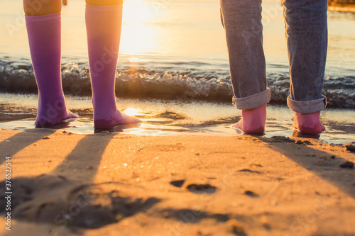 two girls stand on the beach in socks on their bare feet. close-up at sunrise. socks advertising concept