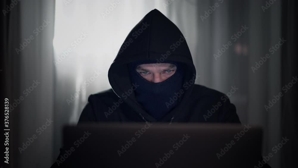 Hacker cracker in the hood in a dark room using computer virus program for cyber attack. Security concept. Hacker cracker in the hood in a dark room using computer virus program for cyber attack. Security concept.