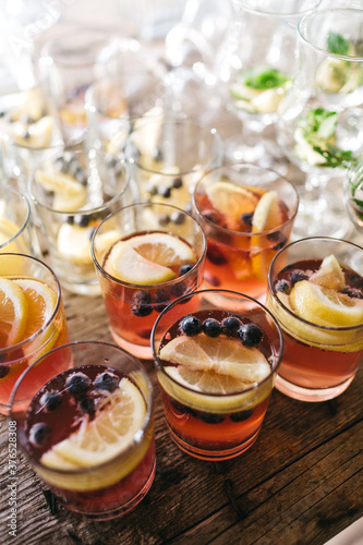 Top view of glasses full of tasty fresh juice with lemon slices and blueberry. Alcohol free delicious drinks on luxury gender party. Sober baby shower celebration. Concept of taste and food. photo