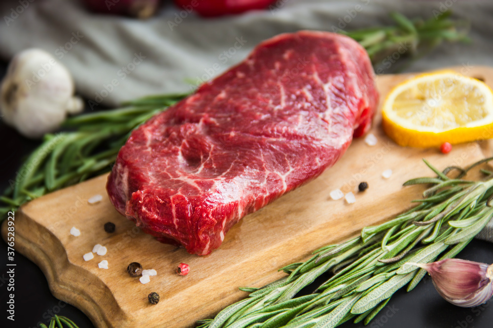 Raw beef steak on a cutting board with spices. Creative atmospheric decoration. Raw beef steak on a cutting board with spices. Creative atmospheric decoration.