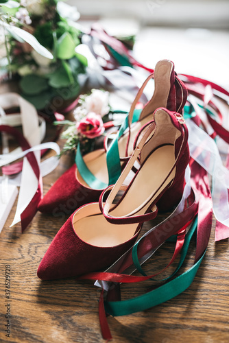 Front view of fashionable red shoes for formal occasion with colorful ribbons. Pretty detail, trendy footwear for elegant gala night. Preparing for meeting. Concept of unique style and woman accessory