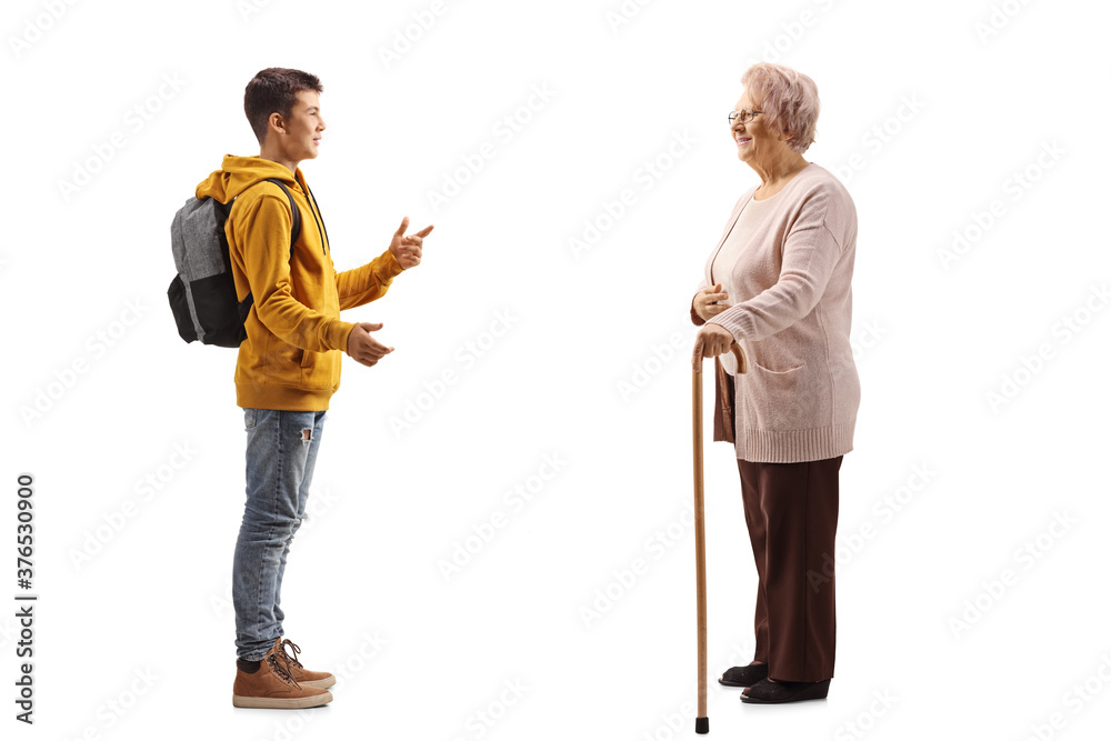 Full length profile shot of a male teenage student talking to an elderly woman Full length profile shot of a male teenage student talking to an elderly woman