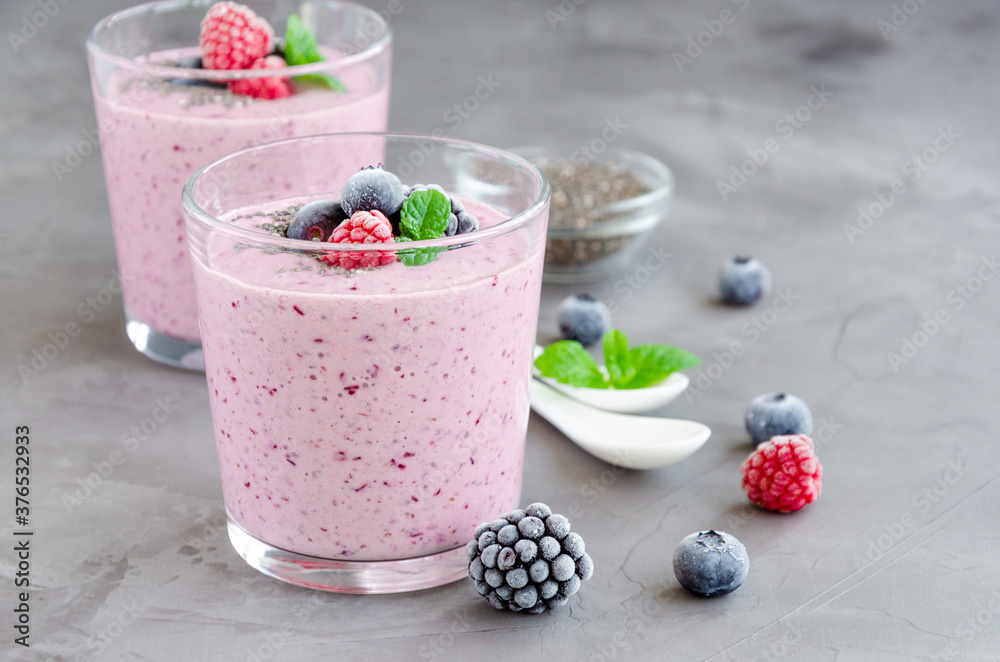 Berry smoothies of yogurt, chia seeds and frozen berries in a glass on a dark concrete background. Healthy food. Copy space. Berry smoothies of yogurt, chia seeds and frozen berries in a glass on a dark concrete background. Healthy food. Copy space.