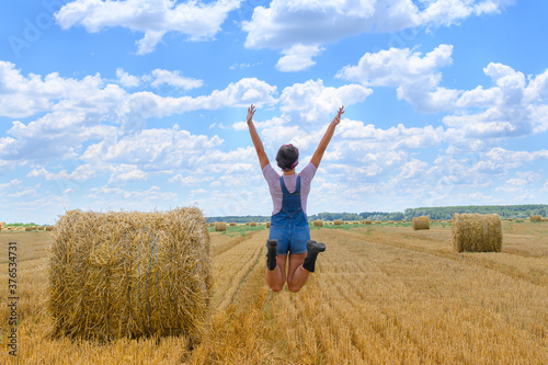 фотографія Young countrywoman enjoying time in golden wheat fields on cloudy, sunny day