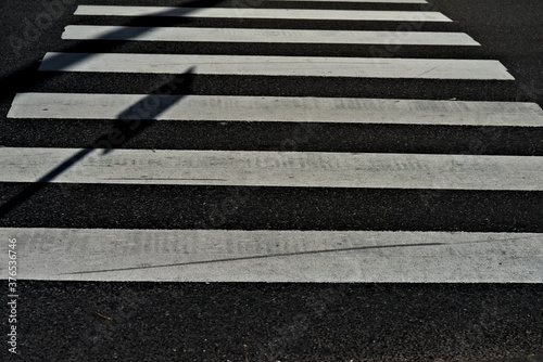 Crosswalk for pedestrians on black asphalt in an urban environment.
