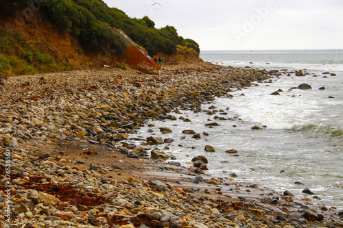 a shot of the lush green and red rock mountain landscape and the rocky beach and the ocean with waves crashing against the rocks at Bluff Cove beach in Palos Verdes California