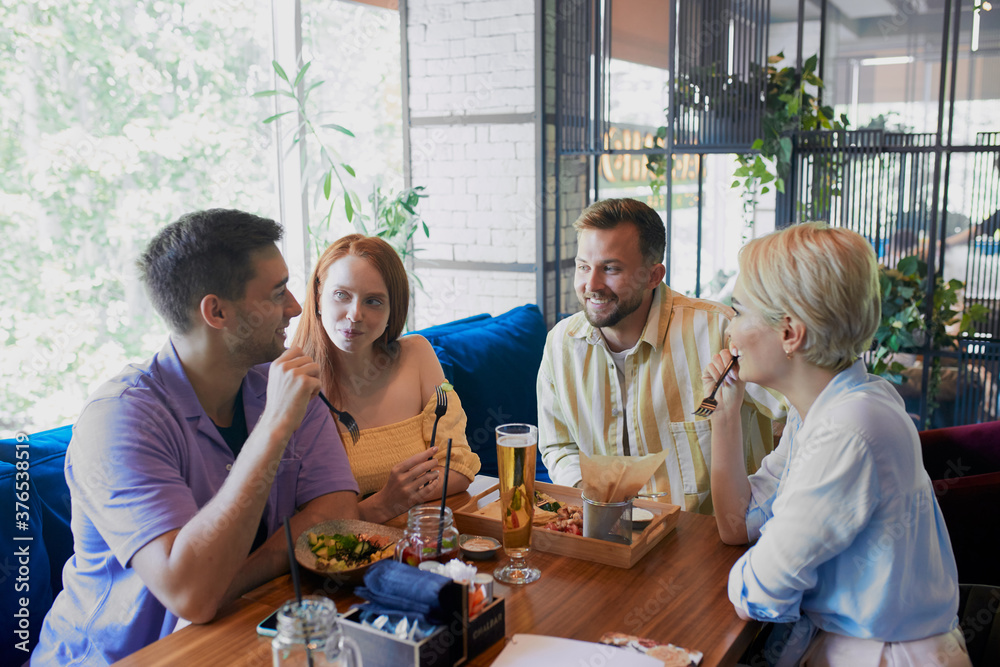 happy caucasian friends did not meet each other in a long time, hold meeting in restaurant or bar, have meal, discuss news