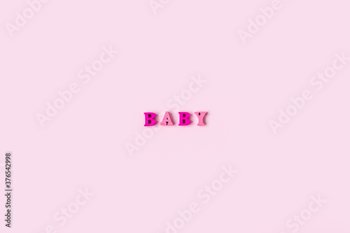 The word BABY is made of wooden letters on a pale pink background. Banner design. Baby shower concept. Photo of minimal background with beeautiful decor and place for text isolated pink background