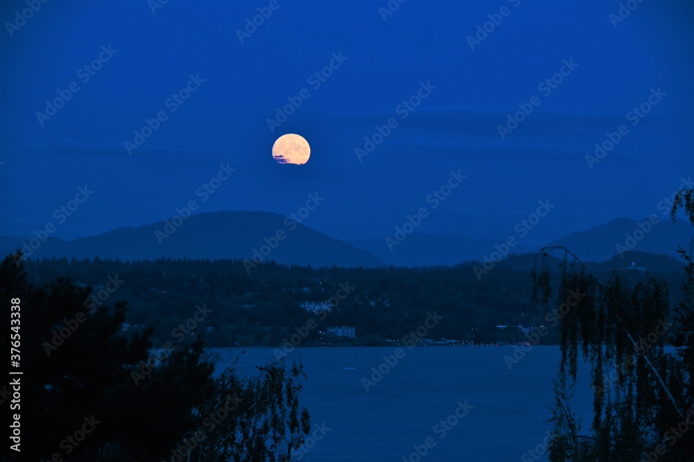 Full moon rising over mountains and lake