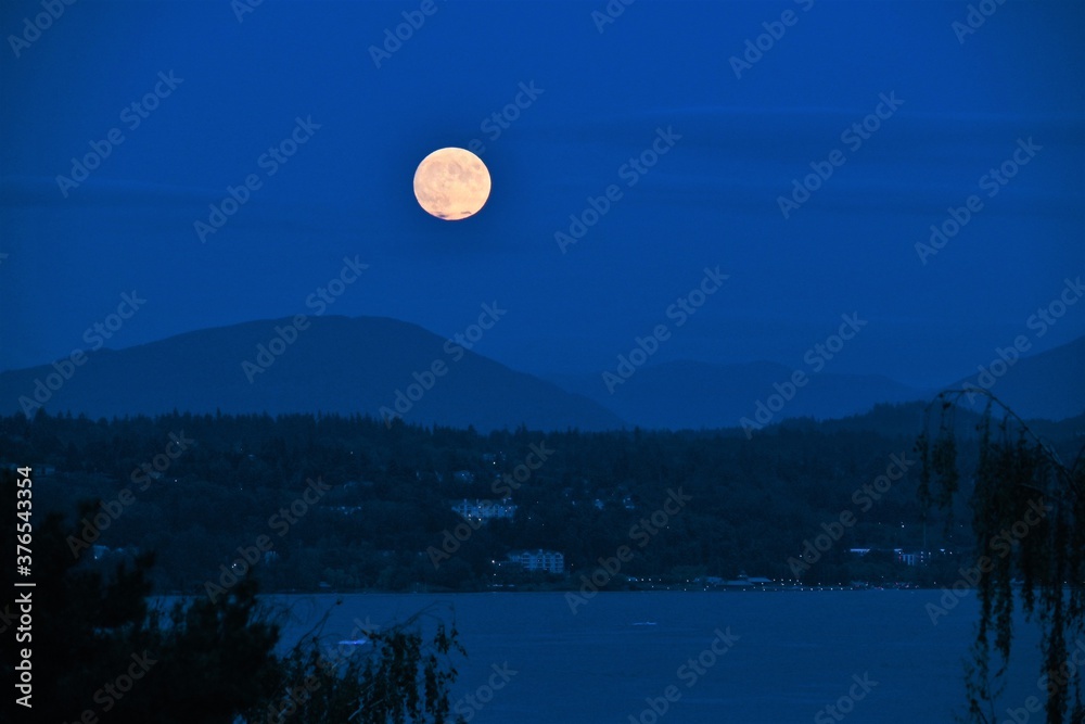 Obraz premium Full moon rising over mountains and lake