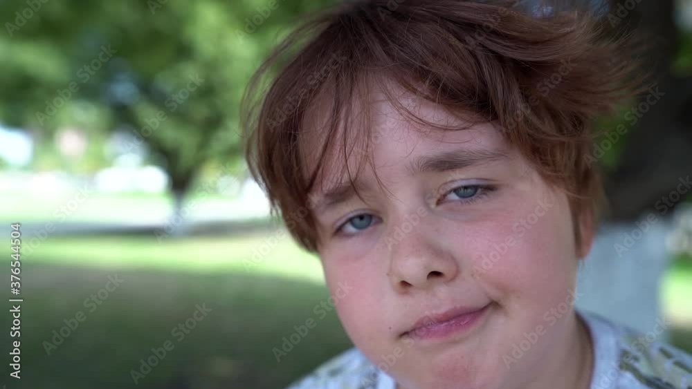 cute funny child with tousled hair, looking at camera in park area at summer, closeup of face cute funny child with tousled hair, looking at camera in park area at summer, closeup of face