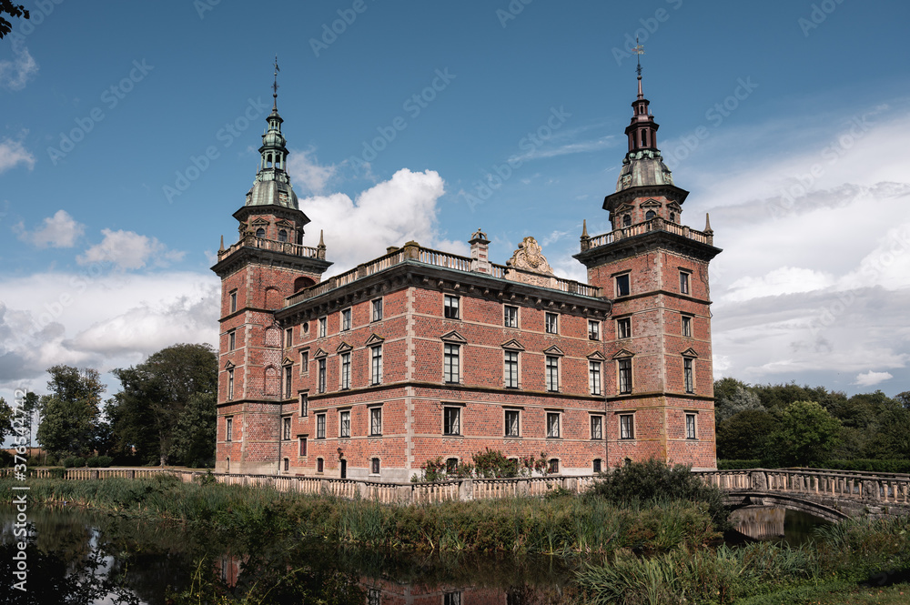 The exterior facade of castle Marsvinsholm with its to towers and the surrounding moat on a warm summer day