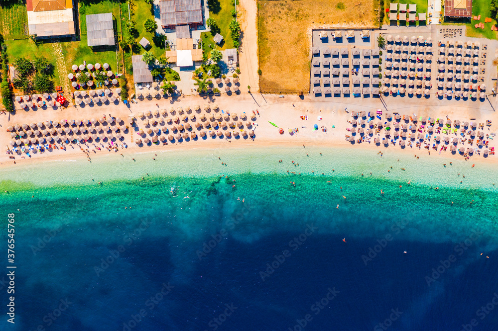 Concept of summer vacation. View from above, stunning aerial view of an amazing beach with beach umbrellas and turquoise clear water. Top view on a sun lounger under an umbrella on the sandy beach