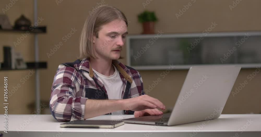 Young man opens laptop to start working from home office. Young man opens laptop to start working from home office.