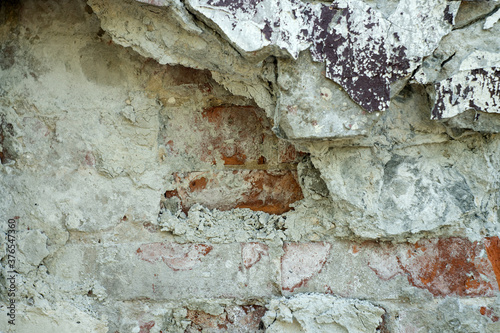 The texture of a white ruined wall from under which the brickwork is visible