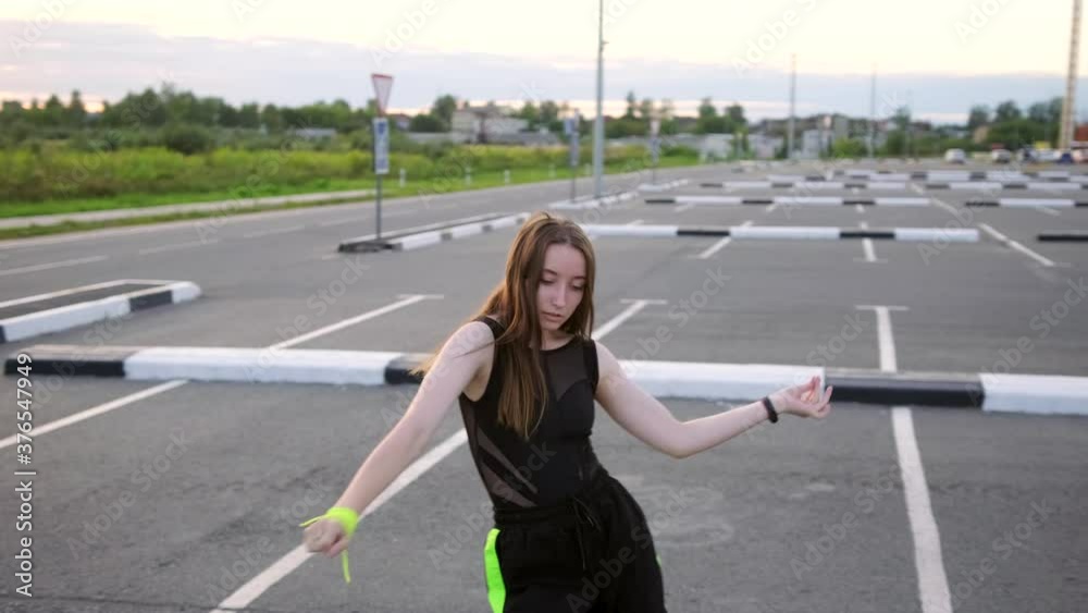 young beautiful dancer with long hair dancing modern youth dance free style in the car parking. Slow motion. Hand camera young beautiful dancer with long hair dancing modern youth dance free style in the car parking. Slow motion. Hand camera