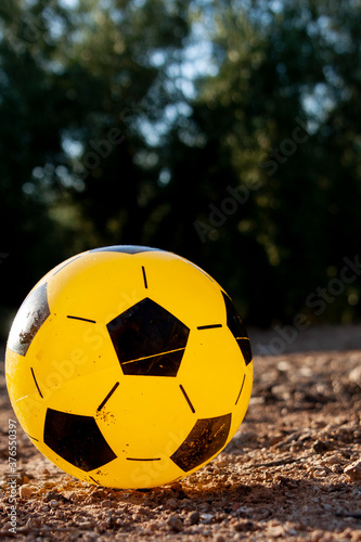 a yellow rubber ball with black pentagons on the field