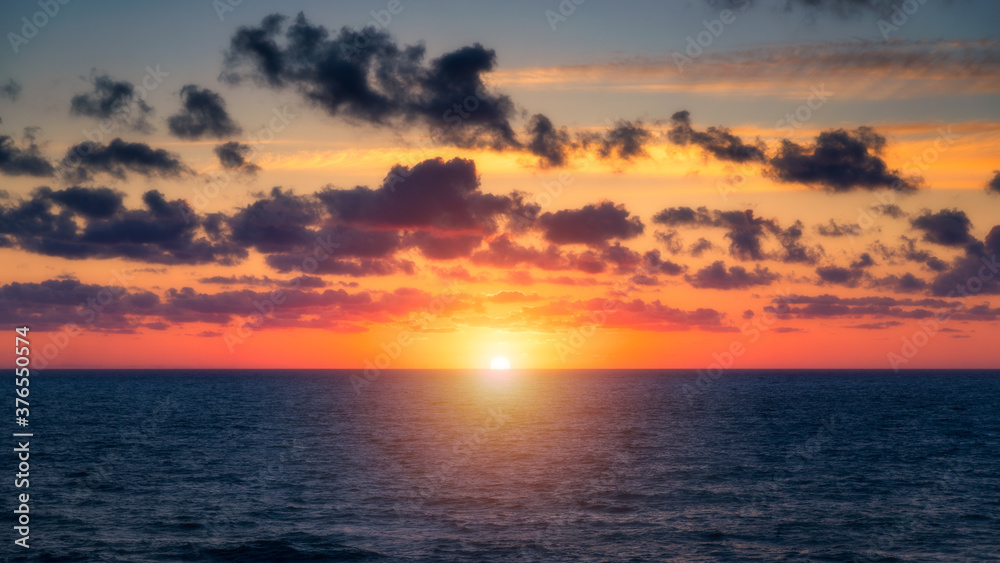 Beautiful sunset/sunrise over the sea. Beautiful sunset over the ocean. Beautiful sunset over sea with reflection in water, majestic clouds in the sky