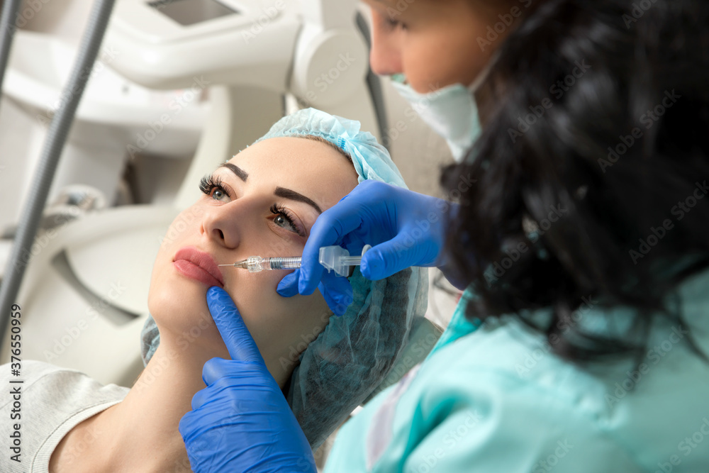 Fototapeta premium cosmetologist making injection in face, lips.