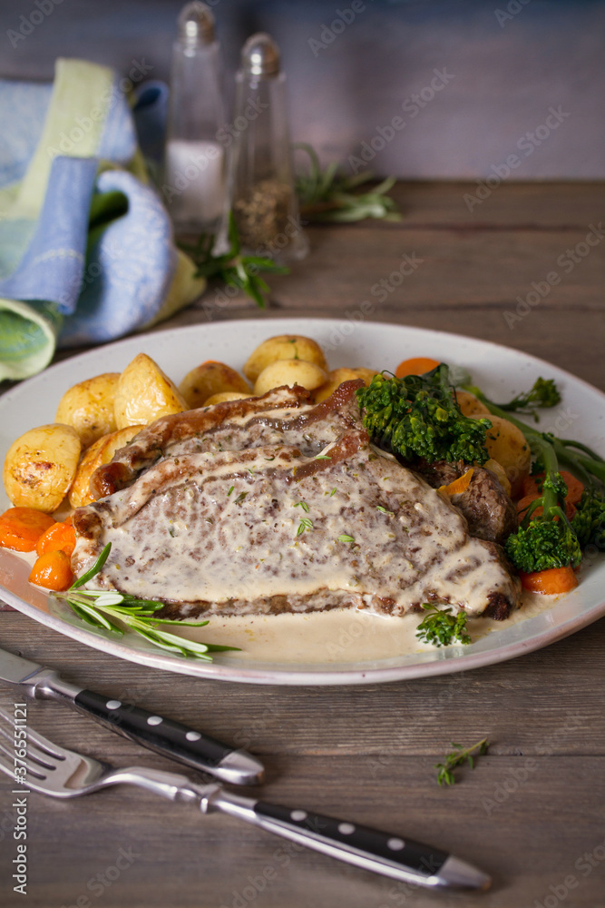 Roast beef steak fillets with creamy Gorgonzola cheese dressing and vegetables on plate. Vertical photo Roast beef steak fillets with creamy Gorgonzola cheese dressing and vegetables on plate. Vertical photo