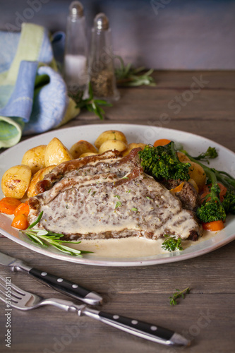 Roast beef steak fillets with creamy Gorgonzola cheese dressing and vegetables on plate. Vertical photo