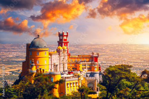 Famous historic Pena palace part of cultural site of Sintra against sunset sky in Portugal. Panoramic View Of Pena Palace, Sintra, Portugal. Pena National Palace at sunset, Sintra, Portugal. photo