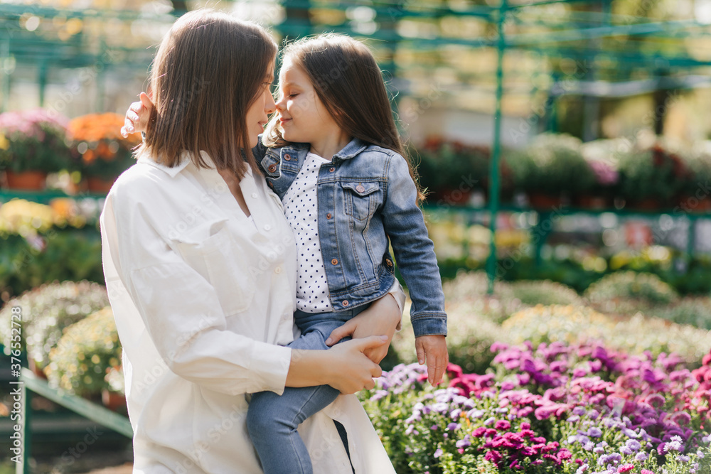 Young mother with child chilling during photoshoot. Short-haired brunette woman holding her daughter. Young mother with child chilling during photoshoot. Short-haired brunette woman holding her daughter.