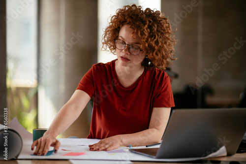 Beautiful businesswoman working on project. Young woman with curly hair in office...