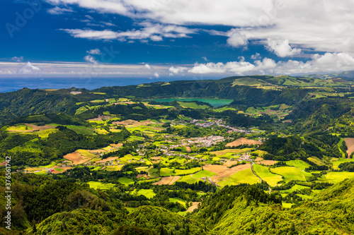 View of Furnas town and lake  Lagoa das Furnas  on Sao Miguel Island  Azores  Portugal from the Miradouro do Salto do Cavalo viewpoint. A tranquil scene of lush foliage and town in a volcanic crater