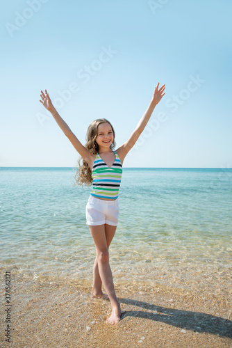 Portrait of beautiful little girl plays n sea waves.