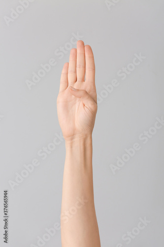 Hand showing letter B on grey background. Sign language alphabet