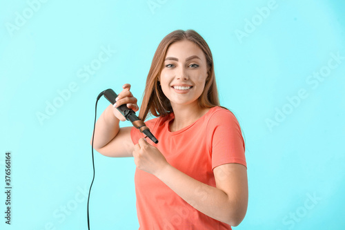 Young woman with curling ir...