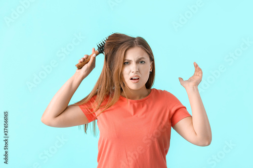 Stressed woman brushing hair on color background
