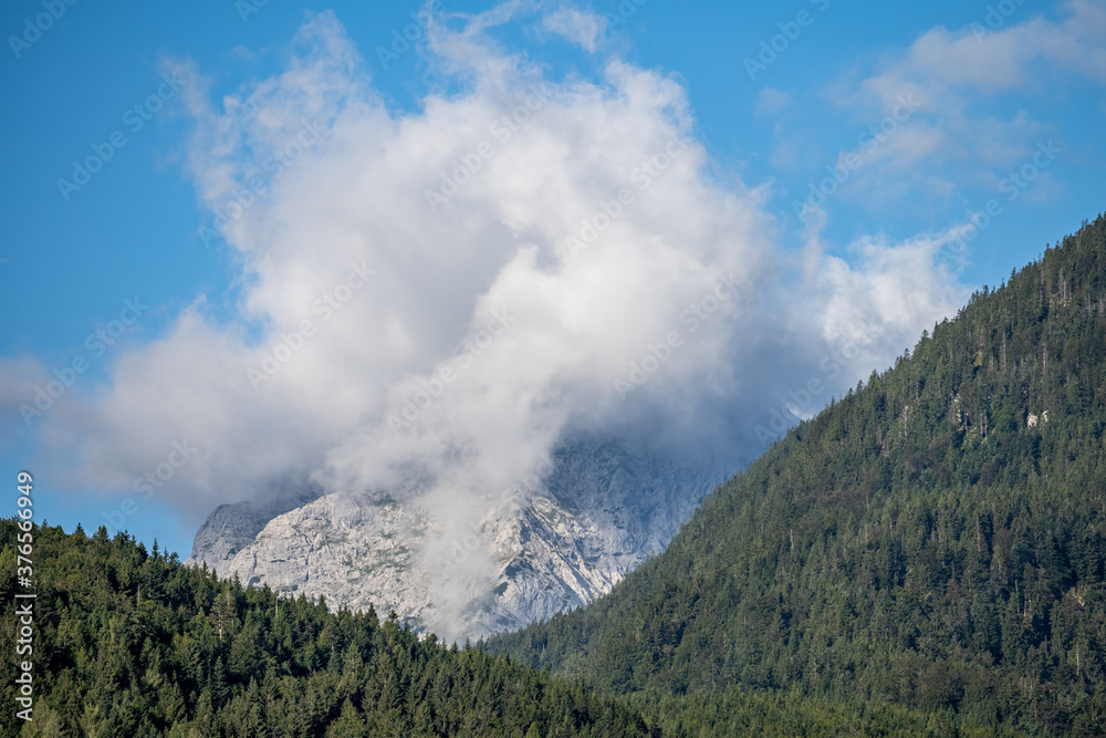 peaks of the wetterstein mountains in the clouds in the early morning, view from mittenwald town