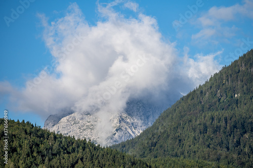 peaks of the wetterstein mountains in the clouds in the early morning, view from mittenwald town