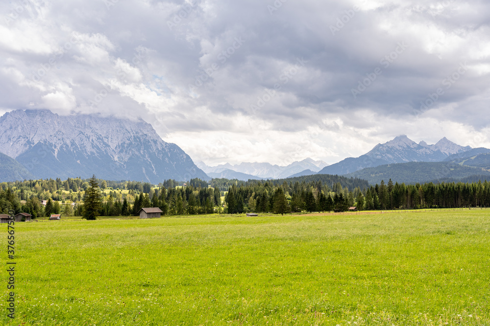 Obraz premium view on wetterstein mountain panorama and wooden houses on a green meadow near mittenwald