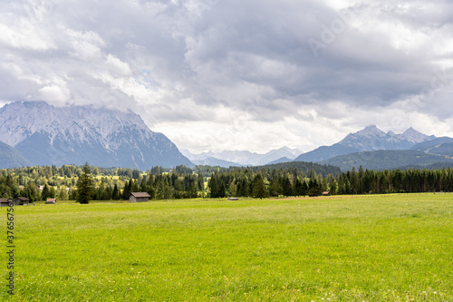 view on wetterstein mountain panorama and wooden houses on a green meadow near mittenwald