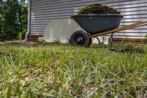 Foto Low angle shot of centipede grass and a wheelbarrow full of sod beside a buildin