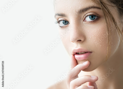 Beautiful young woman with clean perfect skin and water moisture drops touching face. photo