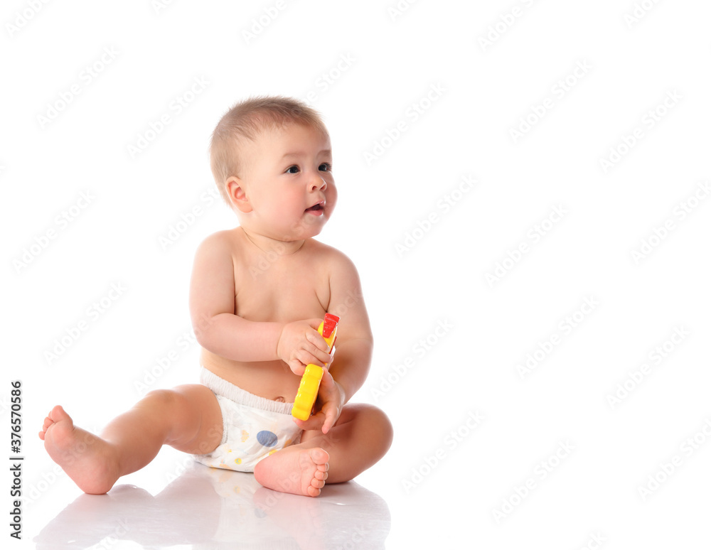 Baby in diaper playing with toy on studio floor Baby in diaper playing with toy on studio floor