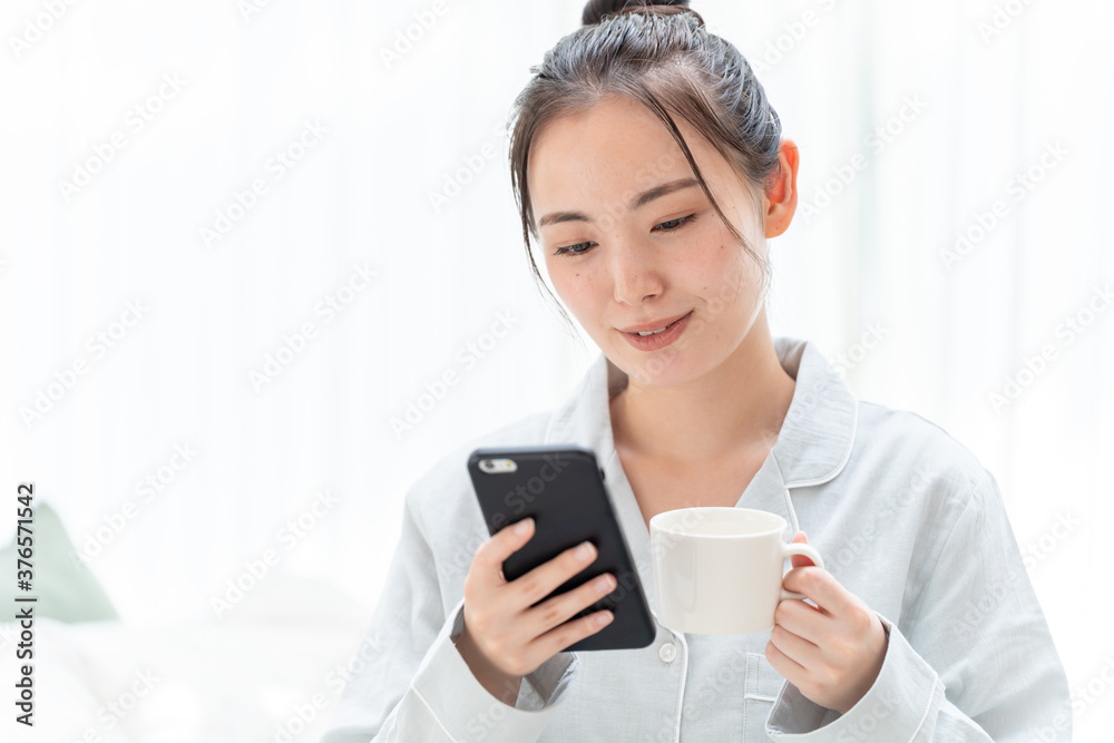 朝にスマートフォンをチェックする女性
